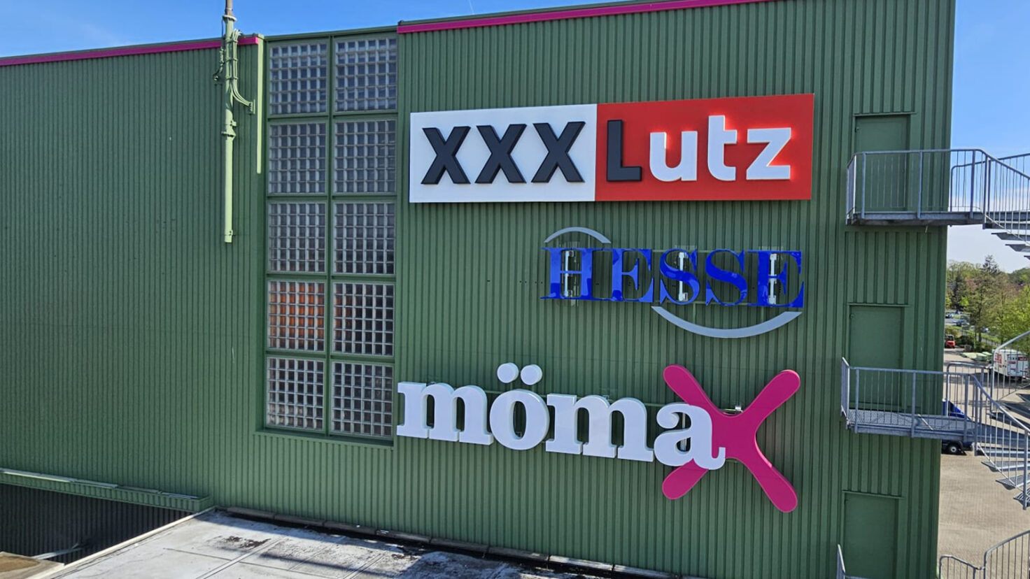 3 verschiedene Logo-Leuchtschriften an der Fassade des XXXLutz in Garbsen, Deutschland
