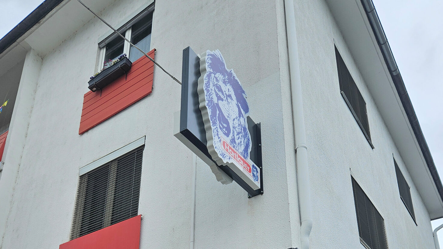 Steckschild an der Fassade der Hartlauer-Filiale in Feldkirchen