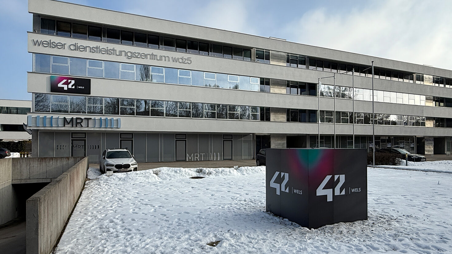 Leuchtender Würfel und Fassaden-Leuchtschild beim Campus 42 in Wels