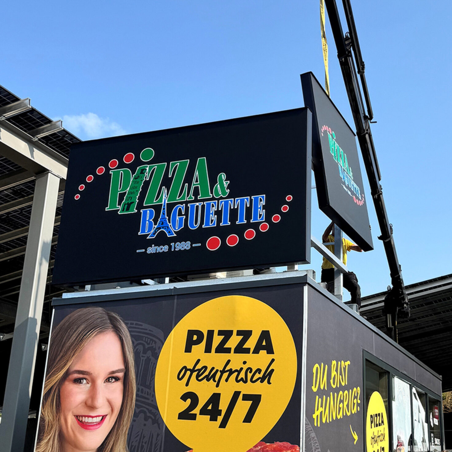 Leuchtschilder am Dach eines Containers der Pizza-Baguette GmbH
