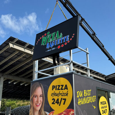 Montage der Leuchtschilder am Dach eines Containers der Pizza-Baguette GmbH